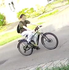 Geblurd camerabeeld van de verdachte jongeman op een groene elektrische fiets in Linne.