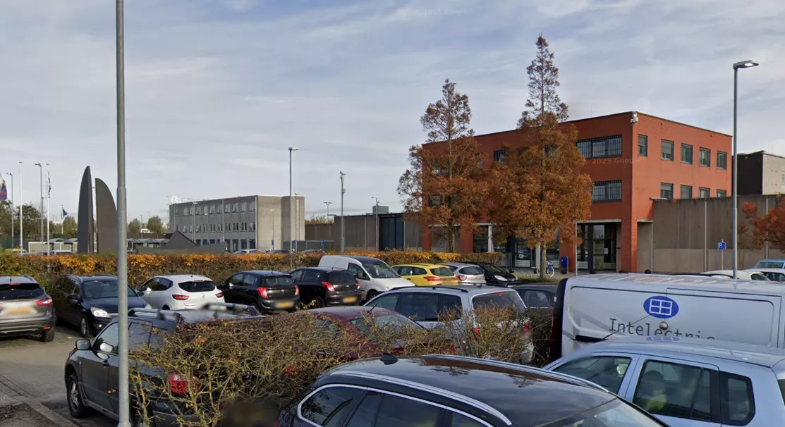 De buitenkant en hoge beveiligingsmuren van een Nederlandse Penitentiaire Inrichting (gevangenis).