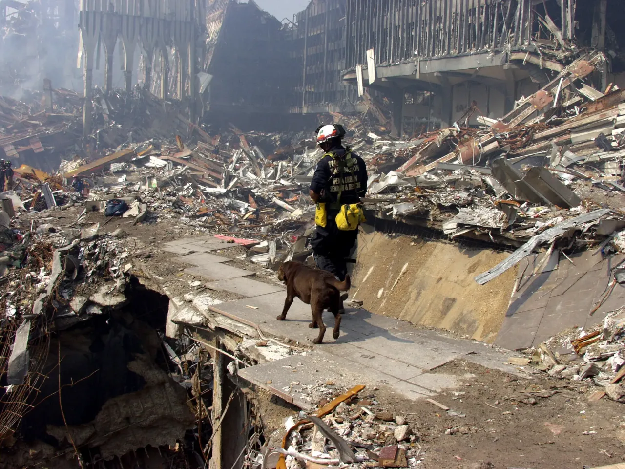 Hulpverleners en brandweerlieden die zoeken naar overlevenden tussen de rokende puinhopen op Ground Zero in New York.