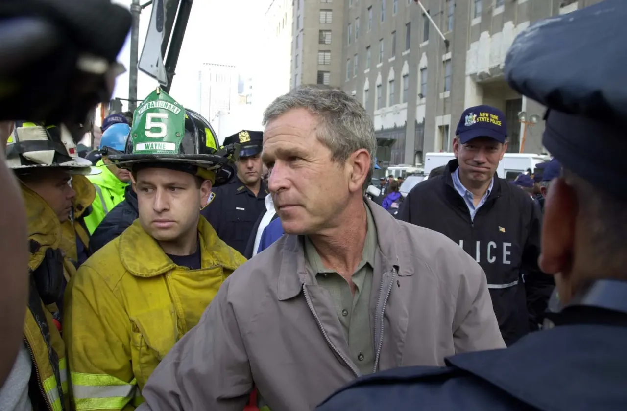 President George W. Bush spreekt hulpverleners toe met een megafoon te midden van de rokende puinhopen op Ground Zero in New York, enkele dagen na 9/11.
