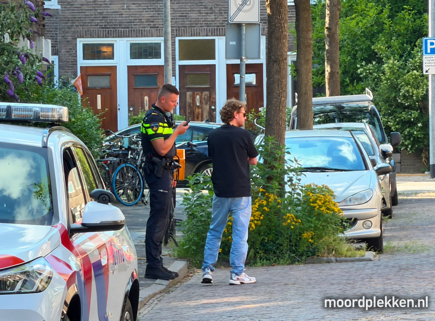 Agenten op straat bij de woning van de verdachte in Groningen op 1 juli 2026, gevolgd door de cameraploeg van tv-presentator Ewout Genemans.