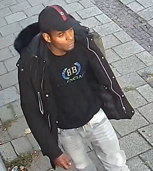 Bewakingsbeeld van de getinte verdachte in een zwarte jas met bontkraag en Balenciaga-trui.