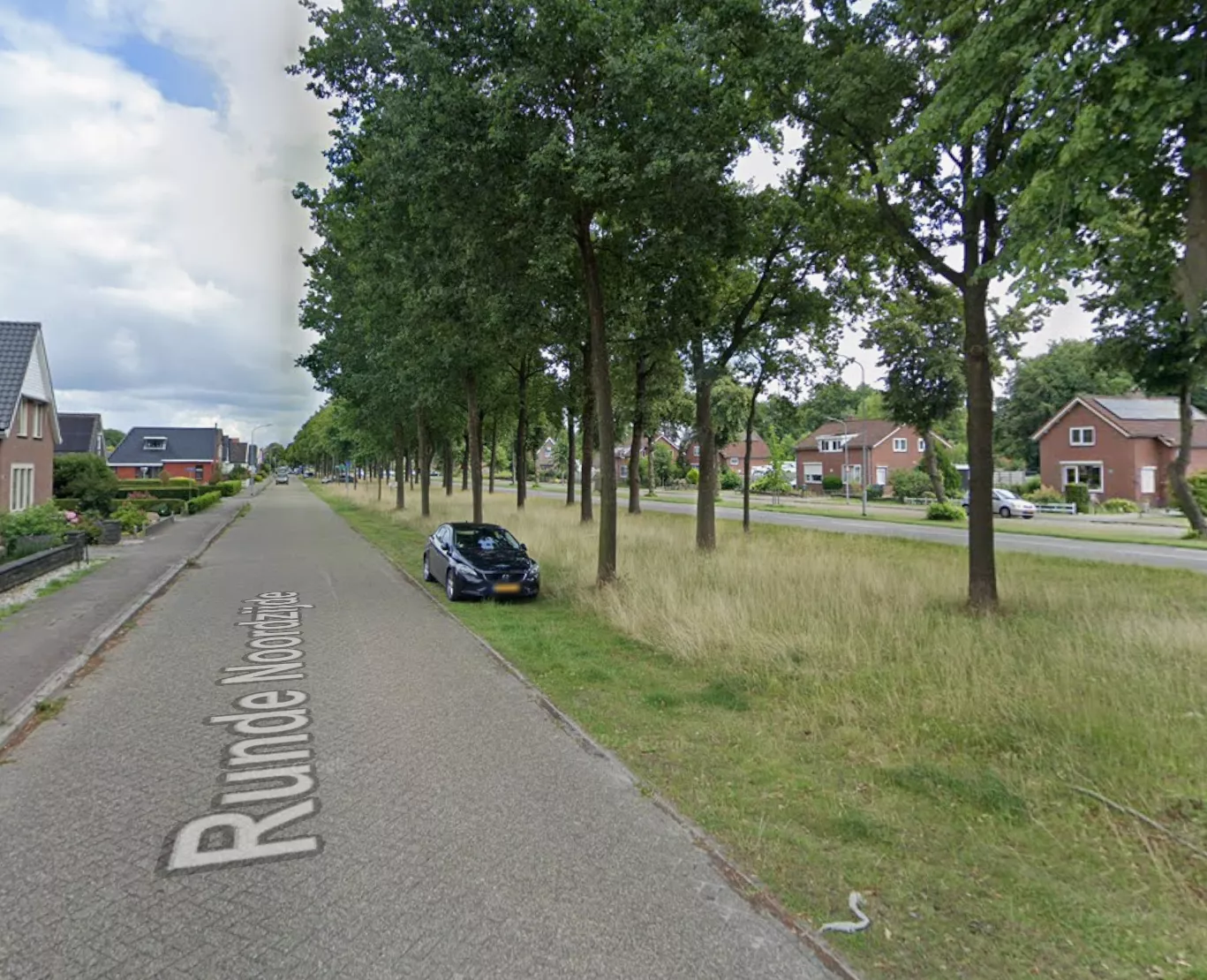 Een overzichtsfoto van de straat Runde Noordzijde in Emmer-Compascuum, waar in het donker een politiewagen met zwaailichten staat.